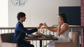 Η αγάπη του νεαρού άνδρα κάνει την πρόταση γάμου στο ευτυχές κορίτσι στην ημερομηνία στη συνεδρίαση εστιατορίων στον πίνακα και τ φιλμ μικρού μήκους Η αγάπη του νεαρού άνδρα κάνει την πρόταση γάμου στο ευτυχές κορίτσι στην ημερομηνία στη συνεδρίαση εστιατορίων στον πίνακα και τ φιλμ μικρού μήκους