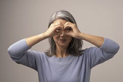Η ασιατική ώριμη γυναίκα κάνει την εντάξει χειρονομία όπως τις διόπτρες στοκ εικόνα Η ασιατική ώριμη γυναίκα κάνει την εντάξει χειρονομία όπως τις διόπτρες στοκ εικόνα