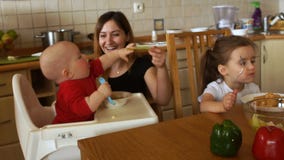 Η μητέρα ταΐζει τη συνεδρίαση μωρών στο highchair Το παιδί δεν θέλει να φάει και αρπάζει ένα κουτάλι με το χέρι του μητέρες φιλμ μικρού μήκους Η μητέρα ταΐζει τη συνεδρίαση μωρών στο highchair Το παιδί δεν θέλει να φάει και αρπάζει ένα κουτάλι με το χέρι του μητέρες φιλμ μικρού μήκους