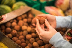 Η νέα γυναίκα επιλέγει το φρέσκο lychee στην υπεραγορά στοκ εικόνες Η νέα γυναίκα επιλέγει το φρέσκο lychee στην υπεραγορά στοκ εικόνες