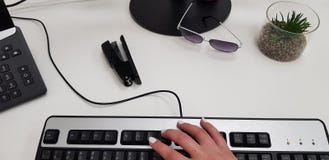 Θηλυκό χέρι στο μαύρο πληκτρολόγιο υπολογιστών κοντά τηλεφωνικό stapler γραφείων στα γυαλιά στοκ εικόνα με δικαίωμα ελεύθερης χρήσης Θηλυκό χέρι στο μαύρο πληκτρολόγιο υπολογιστών κοντά τηλεφωνικό stapler γραφείων στα γυαλιά στοκ εικόνα με δικαίωμα ελεύθερης χρήσης