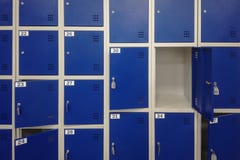 Κύτταρα σε μια μπλε αποθήκευση αποσκευών χρώματος με τα κλειδιά και ένα υπόβαθρο ανοιχτών πορτών στοκ εικόνα Κύτταρα σε μια μπλε αποθήκευση αποσκευών χρώματος με τα κλειδιά και ένα υπόβαθρο ανοιχτών πορτών στοκ εικόνα