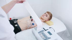 Μια ιατρική κλινική Ένα άτομο που λαμβάνει μια διαδικασία ECG Μια ταινία αποτελεσμάτων απόθεμα βίντεο Μια ιατρική κλινική Ένα άτομο που λαμβάνει μια διαδικασία ECG Μια ταινία αποτελεσμάτων απόθεμα βίντεο
