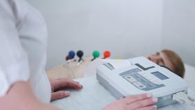 Μια ιατρική κλινική Ένα άτομο που λαμβάνει μια διαδικασία ECG Μια ταινία αποτελεσμάτων που βγαίνει από τη μηχανή απόθεμα βίντεο Μια ιατρική κλινική Ένα άτομο που λαμβάνει μια διαδικασία ECG Μια ταινία αποτελεσμάτων που βγαίνει από τη μηχανή απόθεμα βίντεο