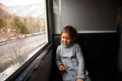 Μικρό κορίτσι στο γκρίζο πουλόβερ που ταξιδεύει με Kukushka το τραίνο στη Γεωργία και που κοιτάζει σε όλο το παράθυρο στοκ φωτογραφία Μικρό κορίτσι στο γκρίζο πουλόβερ που ταξιδεύει με Kukushka το τραίνο στη Γεωργία και που κοιτάζει σε όλο το παράθυρο στοκ φωτογραφία