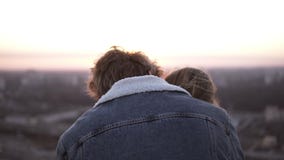 Μοντέρνο ζεύγος Millenial - μακρυμάλλες κορίτσι και blondy άτομο που στέκονται στη θυελλώδη στέγη που αγκαλιάζει με μια όμορφη σκ φιλμ μικρού μήκους Μοντέρνο ζεύγος Millenial - μακρυμάλλες κορίτσι και blondy άτομο που στέκονται στη θυελλώδη στέγη που αγκαλιάζει με μια όμορφη σκ φιλμ μικρού μήκους