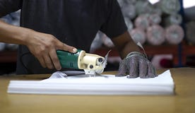 Ο άνδρας εργαζόμενος σε μια κατασκευή ραψίματος χρησιμοποιεί την ηλεκτρική τέμνουσα μηχανή υφάσματος με το γάντι αλυσίδων στοκ εικόνες με δικαίωμα ελεύθερης χρήσης Ο άνδρας εργαζόμενος σε μια κατασκευή ραψίματος χρησιμοποιεί την ηλεκτρική τέμνουσα μηχανή υφάσματος με το γάντι αλυσίδων στοκ εικόνες με δικαίωμα ελεύθερης χρήσης