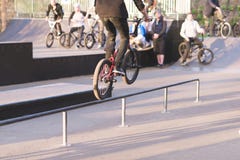 Ο ποδηλάτης BMX κάνει τα τεχνάσματα στις ράγες σε ένα πάρκο σαλαχιών στο υπόβαθρο των ανθρώπων με τα ποδήλατα Άλμα στο bmx στοκ φωτογραφία με δικαίωμα ελεύθερης χρήσης Ο ποδηλάτης BMX κάνει τα τεχνάσματα στις ράγες σε ένα πάρκο σαλαχιών στο υπόβαθρο των ανθρώπων με τα ποδήλατα Άλμα στο bmx στοκ φωτογραφία με δικαίωμα ελεύθερης χρήσης