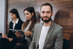 Οι διαφορετικοί νέοι φίλοι σπουδαστών businesspeople που κάθονται μαζί στις καρέκλες στη σειρά αναμονής που χρησιμοποιεί τα κινητ στοκ εικόνες Οι διαφορετικοί νέοι φίλοι σπουδαστών businesspeople που κάθονται μαζί στις καρέκλες στη σειρά αναμονής που χρησιμοποιεί τα κινητ στοκ εικόνες
