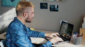 Όμορφο νέο freelancer με τα γυαλιά και την κίτρινη τρίχα που λειτουργούν στο σπίτι, χρησιμοποιώντας ένα lap-top Μοντέρνη επιτυχής φιλμ μικρού μήκους Όμορφο νέο freelancer με τα γυαλιά και την κίτρινη τρίχα που λειτουργούν στο σπίτι, χρησιμοποιώντας ένα lap-top Μοντέρνη επιτυχής φιλμ μικρού μήκους
