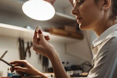τελειότητα Κλείστε επάνω του νέου θηλυκού jeweler που κοιτάζει και που επιθεωρεί ένα δαχτυλίδι στοκ εικόνα με δικαίωμα ελεύθερης χρήσης τελειότητα Κλείστε επάνω του νέου θηλυκού jeweler που κοιτάζει και που επιθεωρεί ένα δαχτυλίδι στοκ εικόνα με δικαίωμα ελεύθερης χρήσης