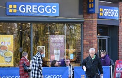 Το Greggs οι αρτοποιοί, με τους πελάτες που κάθονται εξωτερικό και ένα άτομο που περπατά έξω με Greggs παίρνει μαζί τα τρόφιμα κα στοκ εικόνα Το Greggs οι αρτοποιοί, με τους πελάτες που κάθονται εξωτερικό και ένα άτομο που περπατά έξω με Greggs παίρνει μαζί τα τρόφιμα κα στοκ εικόνα