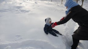 Το Mom σε ένα μαύρο σακάκι ρίχνει έναν μικρό γιο στο χιόνι το χειμώνα φιλμ μικρού μήκους Το Mom σε ένα μαύρο σακάκι ρίχνει έναν μικρό γιο στο χιόνι το χειμώνα φιλμ μικρού μήκους