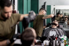 Το βάναυσο άτομο με μια γενειάδα κάθεται μπροστά από τον καθρέφτη σε ένα barbershop Γενειάδα των ατόμων περιποιήσεων κουρέων με τ στοκ εικόνες Το βάναυσο άτομο με μια γενειάδα κάθεται μπροστά από τον καθρέφτη σε ένα barbershop Γενειάδα των ατόμων περιποιήσεων κουρέων με τ στοκ εικόνες
