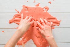 Το κορίτσι μεταθέτει πορτοκαλί slime χεριών του σε έναν άσπρο πίνακα στοκ φωτογραφίες Το κορίτσι μεταθέτει πορτοκαλί slime χεριών του σε έναν άσπρο πίνακα στοκ φωτογραφίες