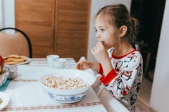 Το μικρό κορίτσι της Νίκαιας που ντύνεται στην πυτζάμα τρώει popcorn στην κουζίνα στοκ φωτογραφία με δικαίωμα ελεύθερης χρήσης Το μικρό κορίτσι της Νίκαιας που ντύνεται στην πυτζάμα τρώει popcorn στην κουζίνα στοκ φωτογραφία με δικαίωμα ελεύθερης χρήσης