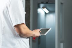 Φωτεινός στενός επάνω του αρσενικού γιατρού σε ομοιόμορφο με το στηθοσκόπιο και τη χρησιμοποίηση της ταμπλέτας υπολογιστών στο νο στοκ εικόνα με δικαίωμα ελεύθερης χρήσης Φωτεινός στενός επάνω του αρσενικού γιατρού σε ομοιόμορφο με το στηθοσκόπιο και τη χρησιμοποίηση της ταμπλέτας υπολογιστών στο νο στοκ εικόνα με δικαίωμα ελεύθερης χρήσης