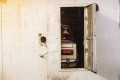 Παλαιό αυτοκίνητο πίσω από τις ανοιχτές πόρτες του γκαράζ σιδήρου στοκ εικόνες Παλαιό αυτοκίνητο πίσω από τις ανοιχτές πόρτες του γκαράζ σιδήρου στοκ εικόνες