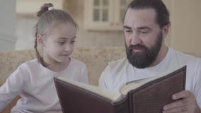 Πορτρέτο της μικρής χαριτωμένης κόρης και της συνεδρίασης πατέρων της στο καθιστικό και να φανεί λεύκωμα φωτογραφιών με τις καλές απόθεμα βίντεο Πορτρέτο της μικρής χαριτωμένης κόρης και της συνεδρίασης πατέρων της στο καθιστικό και να φανεί λεύκωμα φωτογραφιών με τις καλές απόθεμα βίντεο