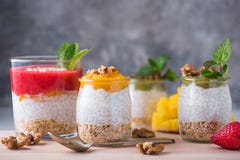 Домодельный пудинг семян Chia и молока миндалины с хлопьями и пюрем кивиа, клубники и манго с грецкими орехами и мятой в стекле стоковое фото rf Домодельный пудинг семян Chia и молока миндалины с хлопьями и пюрем кивиа, клубники и манго с грецкими орехами и мятой в стекле стоковое фото rf