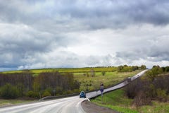 Дорога идет далеко в расстояние, горизонт, немногие автомобили, зеленое поле и лес, пасмурную предпосылку голубого неба стоковое фото Дорога идет далеко в расстояние, горизонт, немногие автомобили, зеленое поле и лес, пасмурную предпосылку голубого неба стоковое фото