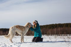 Девушка в зеленой куртке лыжи на ее коленях и русская белая гончая в снежном поле в солнечной зиме стоковые изображения rf Девушка в зеленой куртке лыжи на ее коленях и русская белая гончая в снежном поле в солнечной зиме стоковые изображения rf