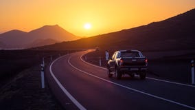 Автомобиль на извилистой дороге управляя к заходу солнца стоковые фотографии rf Автомобиль на извилистой дороге управляя к заходу солнца стоковые фотографии rf