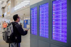 Азиатский человек с путешественником рюкзака используя умный мобильный телефон для регистрации на экране данным по полета в совре стоковая фотография Азиатский человек с путешественником рюкзака используя умный мобильный телефон для регистрации на экране данным по полета в совре стоковая фотография