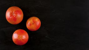 Верхняя часть вниз с взгляда, 3 розовых грейпфрута на черной мраморной доске, знамени с космосом для текста на правильной стороне стоковое фото rf Верхняя часть вниз с взгляда, 3 розовых грейпфрута на черной мраморной доске, знамени с космосом для текста на правильной стороне стоковое фото rf