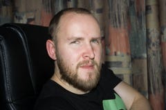 Взрослый человек удобно усажен в поддерживаемый высоко стул компьютера, слушает внимательно стоковые фотографии rf Взрослый человек удобно усажен в поддерживаемый высоко стул компьютера, слушает внимательно стоковые фотографии rf