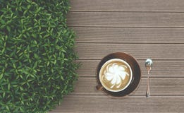 Вкусный выпивать, чашка капучино украшенная с молоком картины цветка вперед в коричневой керамической чашке и нержавеющая ложка ч стоковое изображение Вкусный выпивать, чашка капучино украшенная с молоком картины цветка вперед в коричневой керамической чашке и нержавеющая ложка ч стоковое изображение