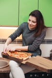 Голодная девушка сидя на кухне имея обедающий итальянской пиццы стоковые изображения Голодная девушка сидя на кухне имея обедающий итальянской пиццы стоковые изображения