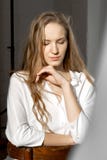 Грустная внимательная модель смотря вниз в белой рубашке стоковая фотография Грустная внимательная модель смотря вниз в белой рубашке стоковая фотография