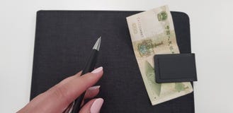Женская рука держа черную ручку на черной папке стоковая фотография Женская рука держа черную ручку на черной папке стоковая фотография