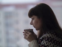 Женщина брюнета выпивает кофе и смотрит вне окно внимательно стоковое фото Женщина брюнета выпивает кофе и смотрит вне окно внимательно стоковое фото