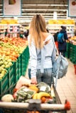 Женщина вытягивает полную вагонетку на супермаркете стоковая фотография Женщина вытягивает полную вагонетку на супермаркете стоковая фотография