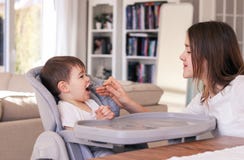 Заботя preteen девушка кормить ее маленький брата сидя в стуле высоты питаясь дома Братья любят и заботят стоковая фотография rf Заботя preteen девушка кормить ее маленький брата сидя в стуле высоты питаясь дома Братья любят и заботят стоковая фотография rf