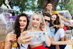 Компания симпатичных друзей смеясь и выпивая желтыми коктейлями, общаясь и делая selfie на таблице внутри стоковое изображение Компания симпатичных друзей смеясь и выпивая желтыми коктейлями, общаясь и делая selfie на таблице внутри стоковое изображение