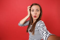 Конец вверх по selfie снятому сотрясенной молодой женщины в striped одеждах держа руку около головы, смотрящ изумил изолированный стоковая фотография Конец вверх по selfie снятому сотрясенной молодой женщины в striped одеждах держа руку около головы, смотрящ изумил изолированный стоковая фотография