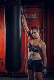 Класс фитнеса Перчатки молодой красивой женщины спорт нося представляя на предпосылке спортзала бокса стоковая фотография Класс фитнеса Перчатки молодой красивой женщины спорт нося представляя на предпосылке спортзала бокса стоковая фотография
