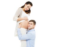 Молодой человек слушая живот на белой предпосылке, беременность его жены беременный женщины стоковые фото Молодой человек слушая живот на белой предпосылке, беременность его жены беременный женщины стоковые фото