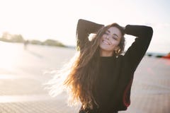 Молодая красивая женщина с длинными танцами вьющиеся волосы и наслаждаться солнечным светом стоковые фотографии rf Молодая красивая женщина с длинными танцами вьющиеся волосы и наслаждаться солнечным светом стоковые фотографии rf