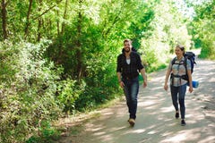 Молодые hikers пар в лесе резвятся человек и женщина с рюкзаками на дороге в природе стоковое фото Молодые hikers пар в лесе резвятся человек и женщина с рюкзаками на дороге в природе стоковое фото