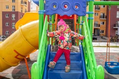 Маленькая девочка, тепло одетая, в играх шляпы и куртки на спортивной площадке со скольжениями и качаниями во дворе residentia стоковые фото Маленькая девочка, тепло одетая, в играх шляпы и куртки на спортивной площадке со скольжениями и качаниями во дворе residentia стоковые фото