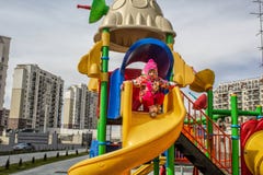 Маленькая девочка, тепло одетая, в играх шляпы и куртки на спортивной площадке со скольжениями и качаниями во дворе residentia стоковые фото Маленькая девочка, тепло одетая, в играх шляпы и куртки на спортивной площадке со скольжениями и качаниями во дворе residentia стоковые фото