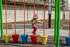 Маленькая девочка, тепло одетая, в играх шляпы и куртки на спортивной площадке со скольжениями и качаниями во дворе residentia стоковое фото Маленькая девочка, тепло одетая, в играх шляпы и куртки на спортивной площадке со скольжениями и качаниями во дворе residentia стоковое фото