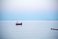 Небольшая рыбацкая лодка на море в раннем утре стоковая фотография rf Небольшая рыбацкая лодка на море в раннем утре стоковая фотография rf
