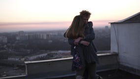 Парень Redhead завихряет его девушку на крыше с горизонтом городского пейзажа и захода солнца на предпосылке Счастливое время сов акции видеоматериалы Парень Redhead завихряет его девушку на крыше с горизонтом городского пейзажа и захода солнца на предпосылке Счастливое время сов акции видеоматериалы