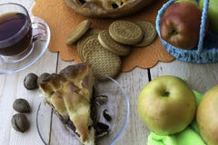 Пирог, кусок яблочного пирога с вишней и грецкими орехами, чашка чаю, яблоки в корзине, грецкие орехи и печенья на таблице стоковые фото Пирог, кусок яблочного пирога с вишней и грецкими орехами, чашка чаю, яблоки в корзине, грецкие орехи и печенья на таблице стоковые фото