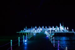 Пристань ночи с шезлонгами, в ярких светах, на море стоковые фото Пристань ночи с шезлонгами, в ярких светах, на море стоковые фото